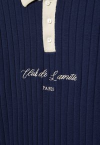 Polo a costine navy con colletto crema e patta con bottoni, ricamato con "Club de Lamitu PARIS" in filo crema.