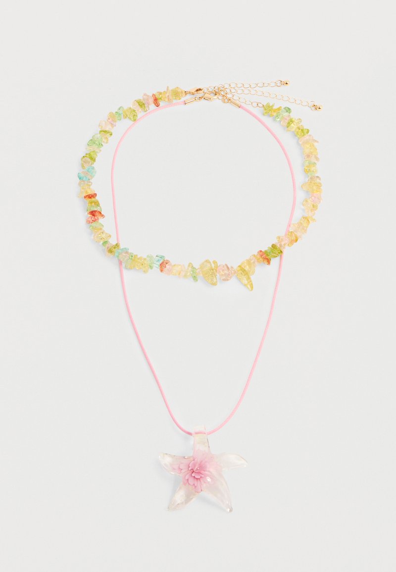 Deux colliers : l'un avec des perles brutes multicolores et une fermeture en or, l'autre un cordon rose avec un pendentif translucide en forme d'étoile portant une fleur rose.