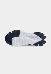Semelle d'une chaussure de sport avec une bande de roulement en caoutchouc segmentée noire et blanche conçue pour la traction et la flexibilité.