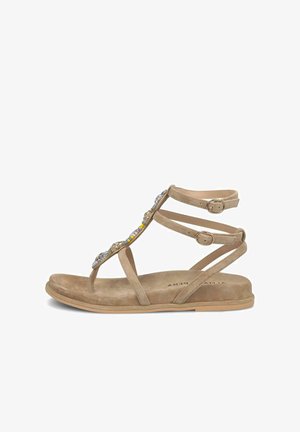Sandalia plana beige con dos hebillas en el tobillo, lazo en el dedo y cuentas y joyas multicolores decorativas a lo largo de la tira vertical.