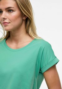 Grön kortärmad t-shirt i mjukt tyg, med rund halsringning och uppvikta ärmslut, med en slät yta och avslappnad passform.