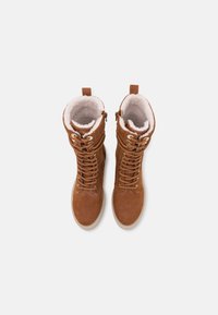 Bottes en daim marron à lacets avec doublure en fausse fourrure, col rembourré et zip sur le côté. Elles sont dotées d'une semelle en caoutchouc plate pour une traction supplémentaire.