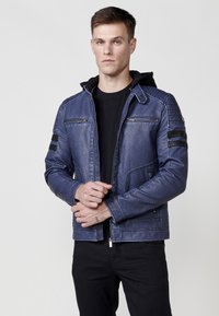 Chaqueta de cuero azul con cierre frontal, dos bolsillos en el pecho y capucha. Presenta acentos de rayas negras en las mangas y un corte relajado.