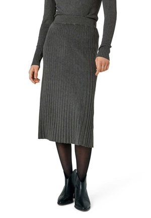 Femme portant une jupe midi côtelée gris foncé, un haut assorti à manches longues côtelées, des collants noirs transparents et des bottines noires.