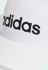 Gorra blanca con visera recta y tejido texturizado. Presenta un gran logo negro de "adidas" en la parte frontal. Detalles cosidos a lo largo de la visera.