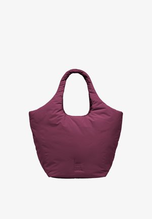 Grand sac fourre-tout rembourré de couleur bordeaux profond avec de larges poignées et une texture de tissu doux, debout contre un fond blanc.