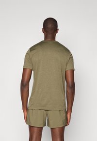 Olivno zelen T-shirt s kratkimi rokavi in okroglo ovratnikom, izdelan iz lahkotnega materiala; v kompletu s popolnoma ujemajočimi se kratkimi hlačami z elastičnim pasom.
