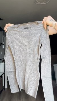 Suéter gris de manga larga con canalé, cuello redondo y aberturas laterales. Fabricado en un material suave, con un acabado texturizado y un ajuste casual.
