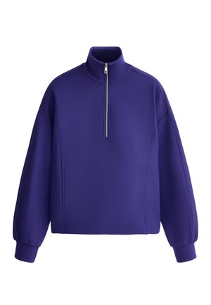 Fialový pulóver s dlhým rukávom, vysokým golierom a polovičným predným zipsom, s rebrovanými manžetami a voľným strihom.