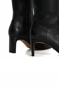 Black leather heeled boots with a smooth texture, rounded toe, and a side zipper; medium stiletto heel with a durable outsole.