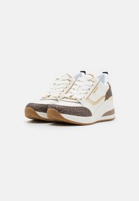 Chaussures de sport blanches et brunes avec un motif texturé brun, des accents dorés et une semelle en caoutchouc blanche. Présente un design à lacets et une languette rembourrée.