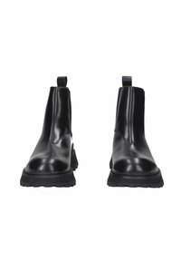 Stivaletti Chelsea in pelle nera con pannelli elastici laterali, linguetta sul retro e suola in gomma spessa per una maggiore aderenza. Finitura liscia e lucida.