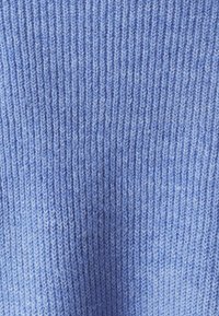 Svetlomodrá pletená látka s textúrou vertikálneho rebrovania. Jemný, ľahký materiál s hladkým povrchom.