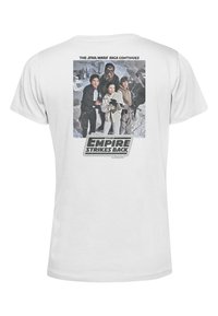 Hvid bomulds t-shirt med et grafisk print af figurer fra "The Empire Strikes Back," med tekst ovenfor og en film-logo nedenfor.