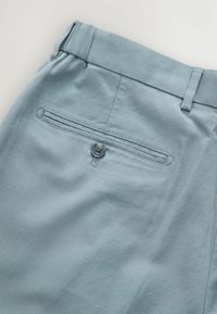 Lichtblauwe geweven broek met een gemêleerd oppervlak, voorzien van een achterzak met knoopsluiting en een brede tailleband.