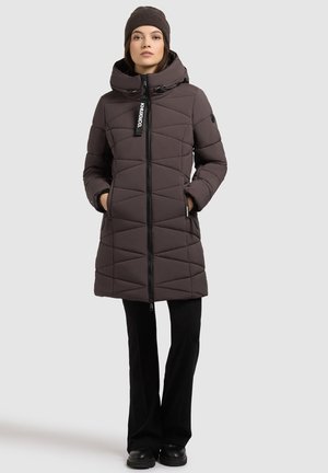 Padded brown outerwear with a high collar, diagonal quilted pattern, black zip, and side pockets. Paired with black pants and boots.