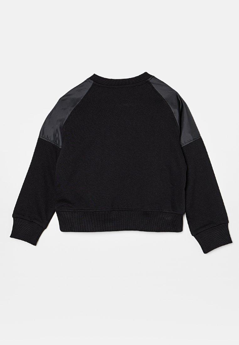 Sweatshirt noir avec un design cropped, présentant un tissu mat et des accents en satin brillant sur les épaules. Poignets et ourlet côtelés.