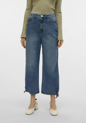 Jeans in denim blu chiaro a gamba larga con vita alta, dotati di bottone frontale, passanti per cintura e tasche laterali; orlo con lacci alle caviglie.