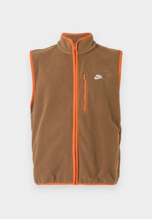 Fleeceväst i brunt med orange detaljer och dragkedja. Har en hög krage och en liten vit logotyp på vänster bröst.