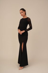 Black dress with long lace sleeves, fitted bodice, and a high slit on the left side. Smooth texture and floor-length design.