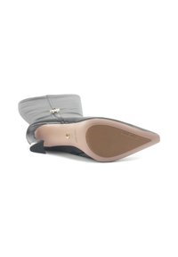 Boots negre din piele, cu vârful ascuțit, toc cu forme suprapuse și o textură netedă. Acestea prezintă un fermoar decorativ și un brand pe talpă.