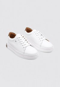 Baskets en cuir blanc avec une finition lisse, bout rond et système de laçage. Accents en cuir marron au talon et panneau latéral texturé.