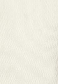 Biały, teksturowany materiał z wzorem wafla, prezentujący miękki, tkany wygląd. Powierzchnia jest gładka i lekko wypukła.