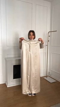 Satin krämfärgade byxor med vida ben och en knapp i midjan. Slät textur, golvlång, med sidofickor för ökad rörelse.