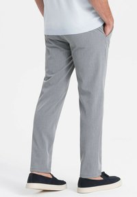 Harmaat kudotut housut suoran lahje- muotoilulla, joissa on sileä pinta ja sivutaskut, yhdistettynä tummansinisiin liukuvaan kenkäpariin.