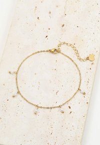 Złota bransoletka łańcuszkowa z małymi akcentami białych pereł i zaokrąglonych złotych koralików. Zawiera zapięcie typu homar z przedłużonym łańcuszkiem.