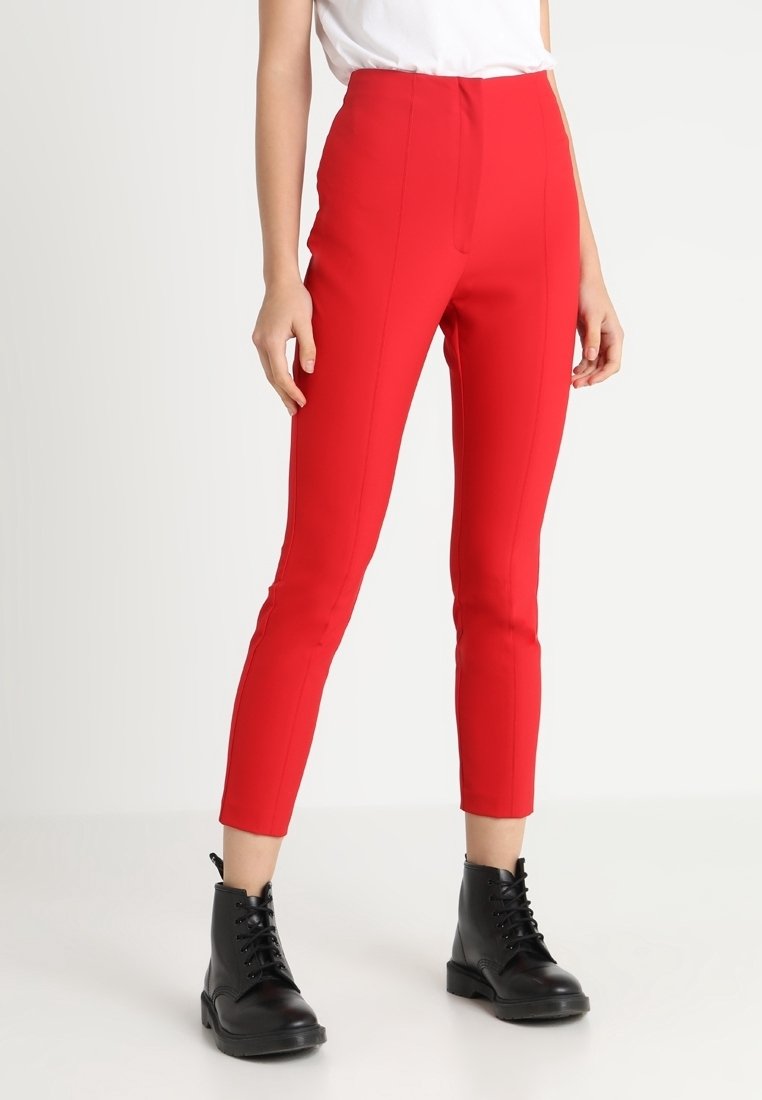 Rode aansluitende broek met hoge taille, voorzien van verticale naden voor structuur en een gladde textuur, gecombineerd met zwarte combatlaarzen.