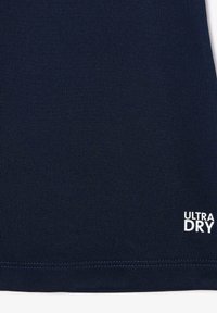 T-shirt de sport bleu marine avec un tissu lisse et texturé, portant l'inscription "ULTRA DRY" en blanc dans le coin inférieur droit.