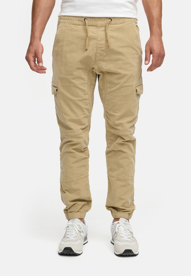 Pantalones cargo beige con cintura elástica y cordón, que cuentan con bolsillos laterales y puños ajustados, fabricados en material de algodón.