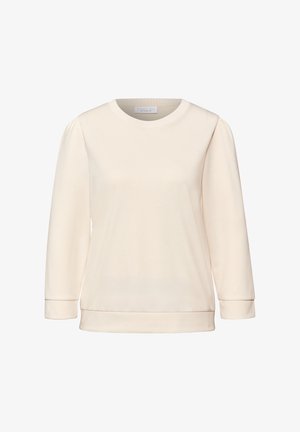 Jasnobeżowa bluza z okrągłym dekoltem, rękawami o długości do połowy przedramienia i gładką, miękką fakturą. Mankiety i dół wykończone prążkowanym ściągaczem.