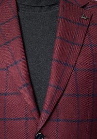 Burgundowy żakiet w kratę z teksturowanym splotem, z niebieskimi liniami, klapami i pojedynczym zapięciem na guzik na ciemnoszarym swetrze.