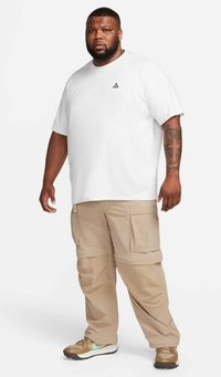 Vit bomulls T-shirt med en liten svart logotyp på bröstet, kombinerad med beige cargobyxor med flera fickor och en lös passform.