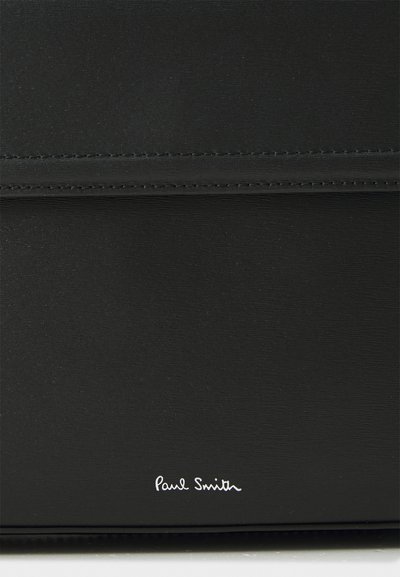 Sort lædertaske med glat tekstur, der har stikninger og en sølvfarvet "Paul Smith" signatur i bunden.