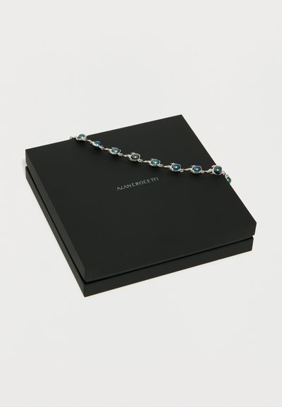 Ασημένιο βραχιόλι με μπλε πέτρες τοποθετημένο πάνω σε κλειστό μαύρο κουτί κοσμημάτων MANCROETTI σε λευκό φόντο.