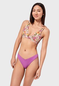 Top de bikini floral con tirantes ajustables en tonos de rosa, naranja y verde, combinado con braguitas de cintura alta de color púrpura sólido.