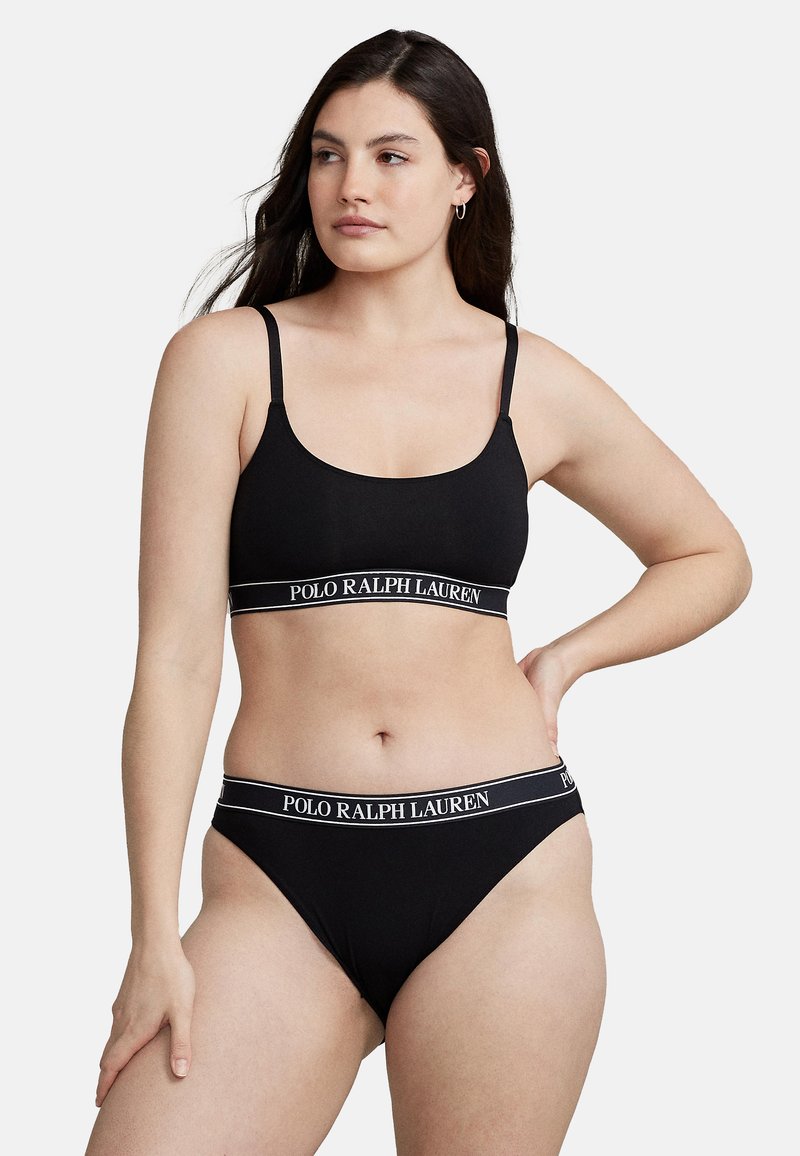 Conjunto de bralette y bikini negro con tirantes finos; cuenta con una banda en contraste con el logo "POLO RALPH LAUREN". Tejido suave y elástico.