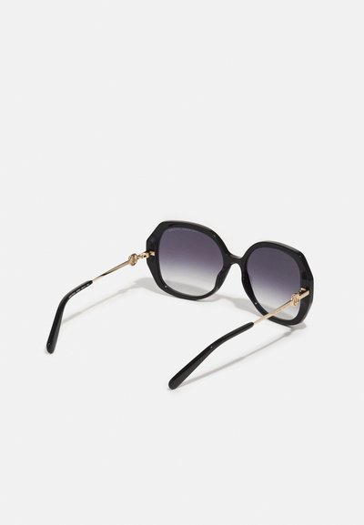 Schwarze achteckige Sonnenbrille mit Verlaufslinsen, goldenen Metallakzenten und eleganten schwarzen Bügeln. Sie verfügt über glatte Kunststoffrahmen und zarte Scharniere.