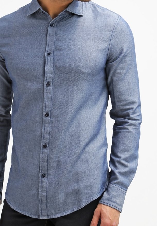Chemise à manches longues avec boutons, en tissu denim bleu clair. Caractéristiques : col pointu, boutons foncés et ourlet arrondi. Texture lisse.