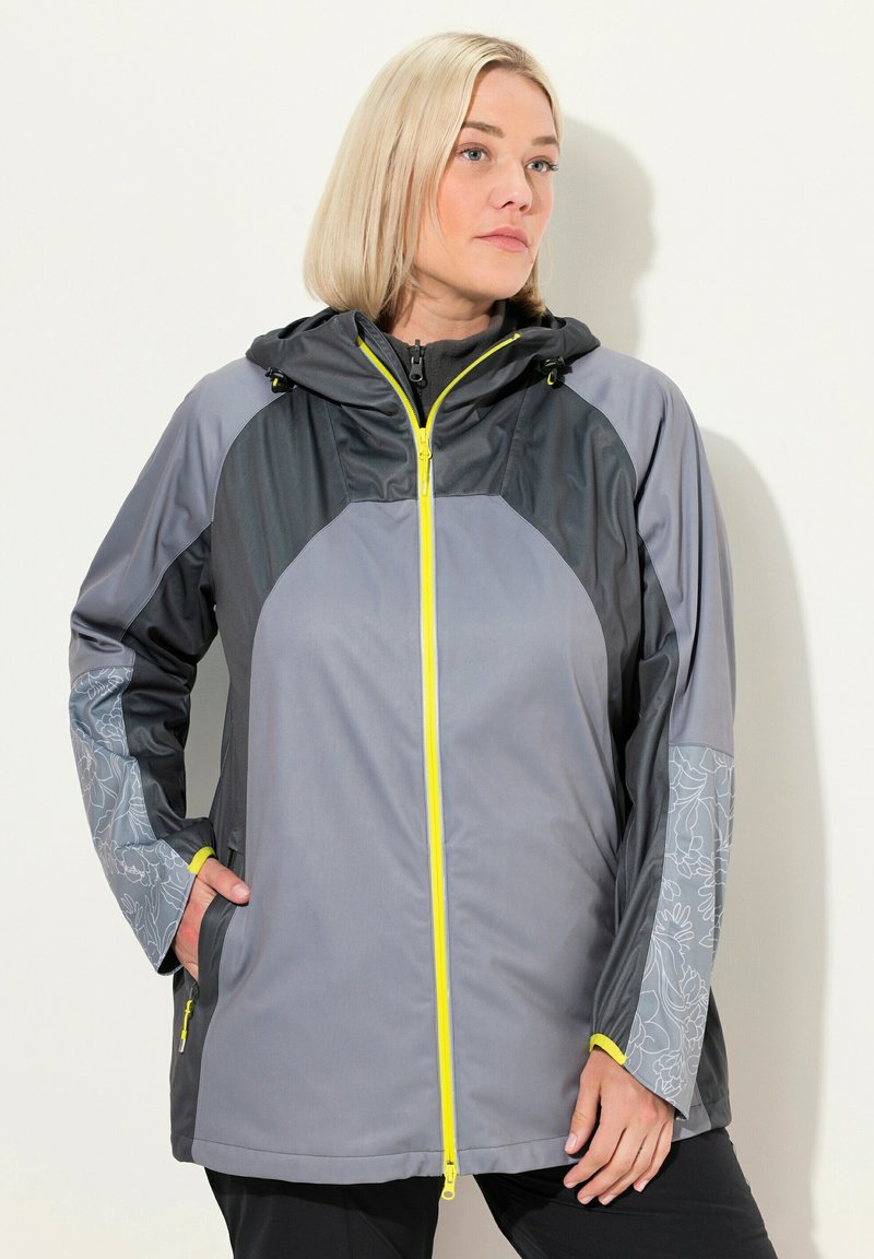 Veste zippée grise avec capuche, présentant des accents jaunes, des manches à motif floral et un mélange de textures mates et brillantes.