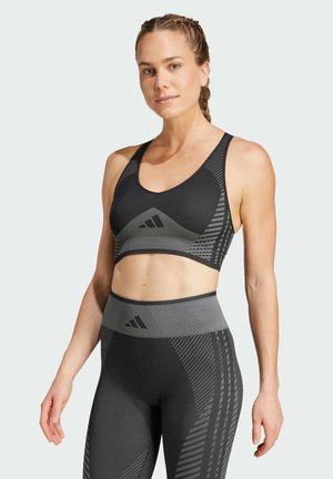 Reggiseno sportivo nero con motivi geometrici grigi, caratterizzato da spalline larghe e scollatura a forma di U, abbinato a leggings a vita alta coordinati.