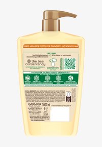 Bottiglia a pompa in plastica beige con bordi arrotondati, capacità di 1000 ml. Etichette verdi e arancioni con testo in tedesco, codice QR e lista degli ingredienti.