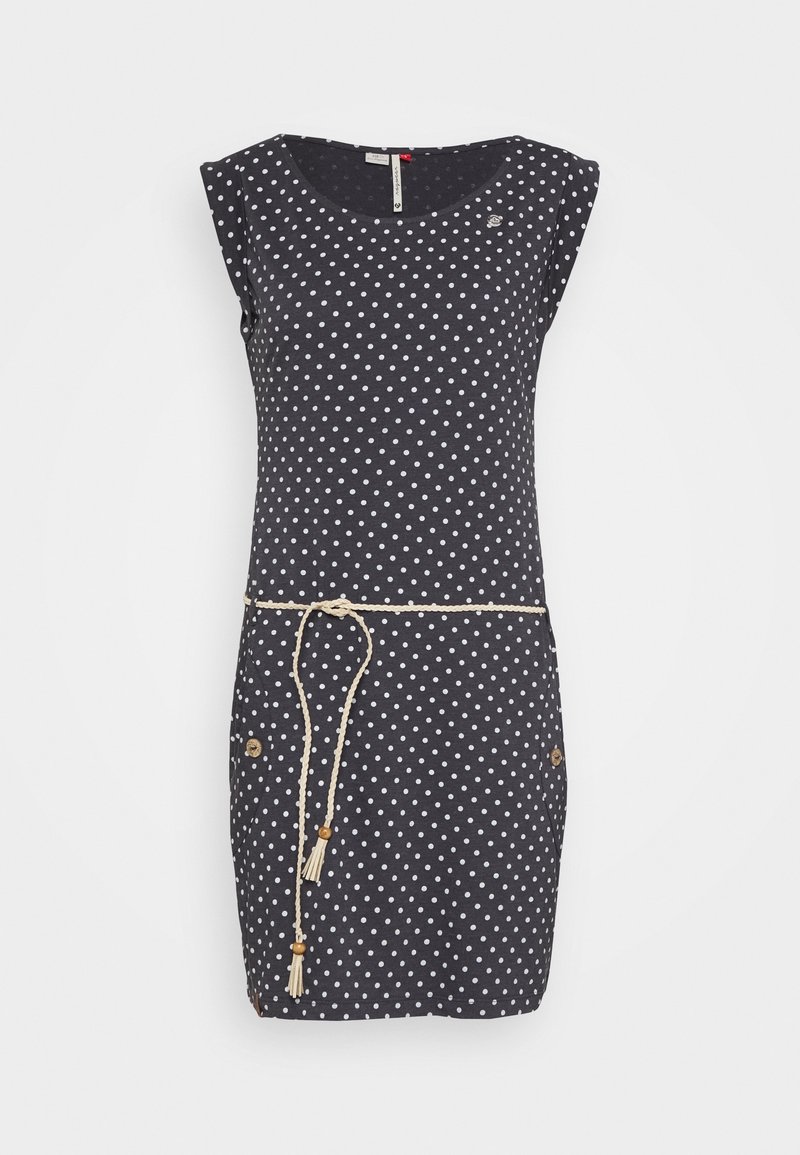 Robe noire sans manches à pois blancs et une fine ceinture tressée beige attachée à la taille, avec des poches boutonnées des deux côtés.