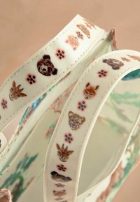 Torba płócienna z kolorowymi nadrukami twarzy zwierząt i odciskami łap na rączkach. Projekt na jasno tle z miękką teksturą.