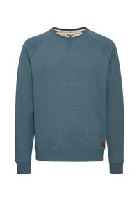 Sudadera de algodón azul con mangas largas, escote redondo y puños de canalé. Presenta una textura sutil y una pequeña etiqueta de tela marrón en el dobladillo.