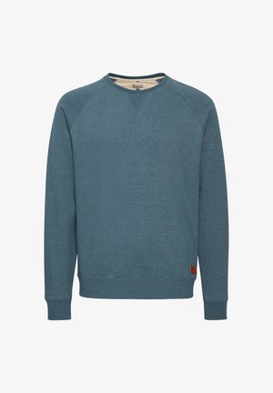 Kék pamut pulóver, hosszú ujjakkal, kerek nyakkivágással és bordázott mandzsettával. Finom textúrával rendelkezik, és egy kis barna szövet címke található az alján.