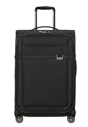 Black suitcase with a textured fabric exterior, side handle, retractable handle, front pocket, and four spinner wheels for mobility.